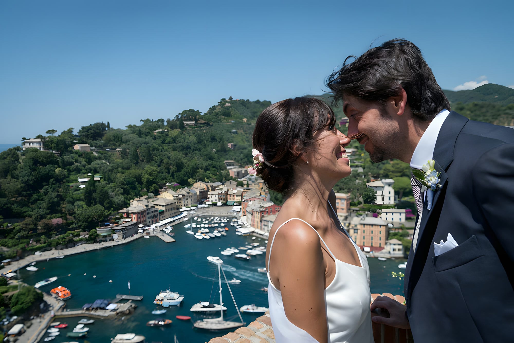 Gli sposi su una terrazza alta sopra il porto di Portofino, con le barche ormeggiate sotto