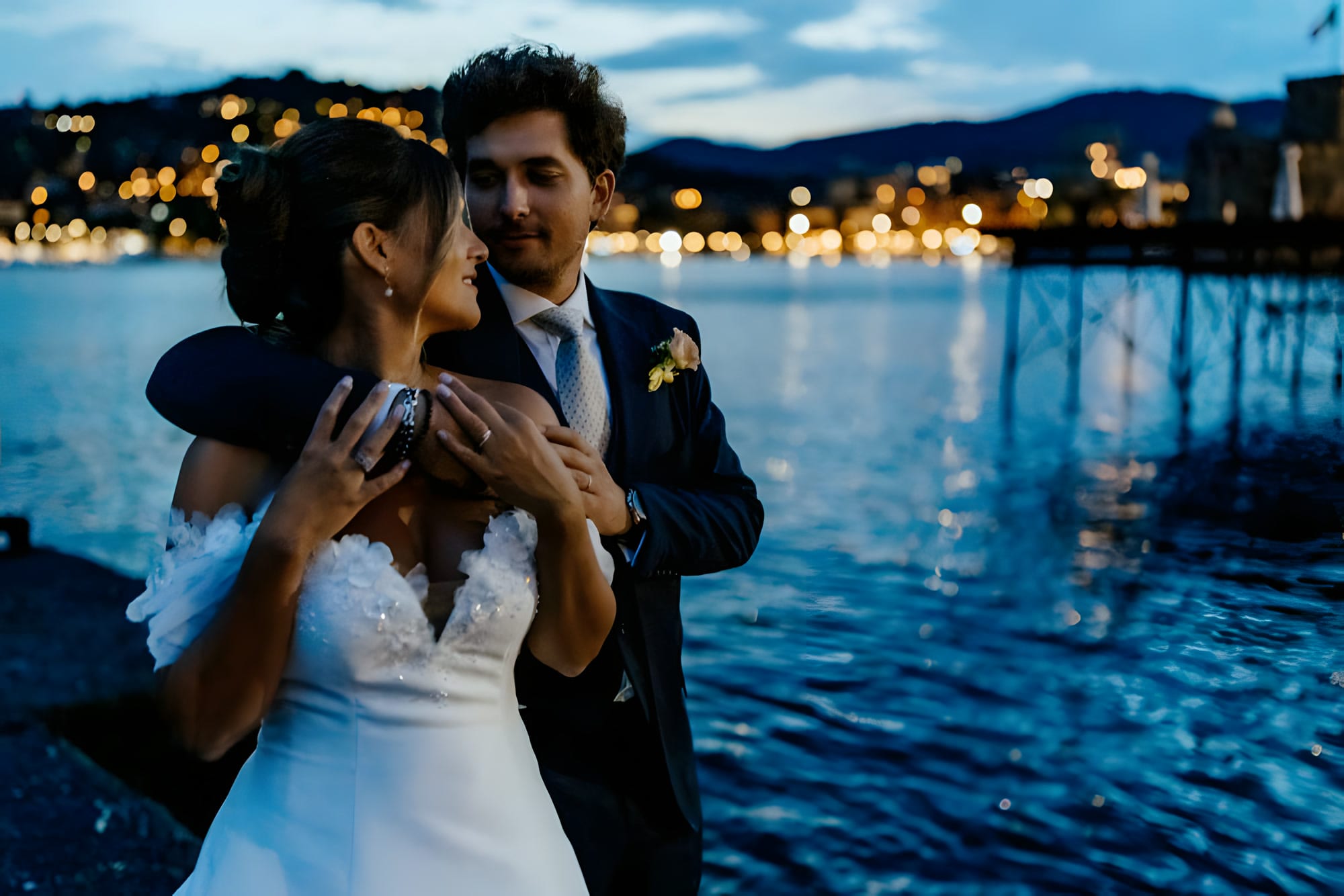 Gli sposi di notte in riva all'acqua, con le luci del lungomare alle spalle